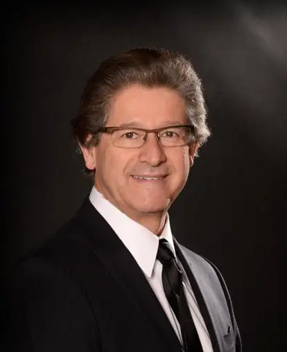 Smiling man in suit and glasses.