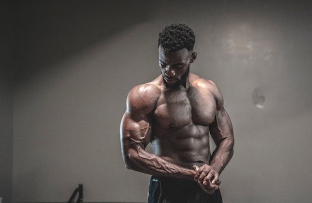 Muscular man flexing in dimly lit gym.