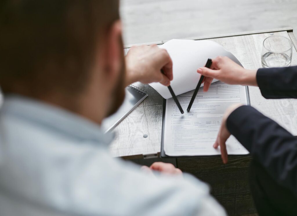 Two people discussing documents with pens.