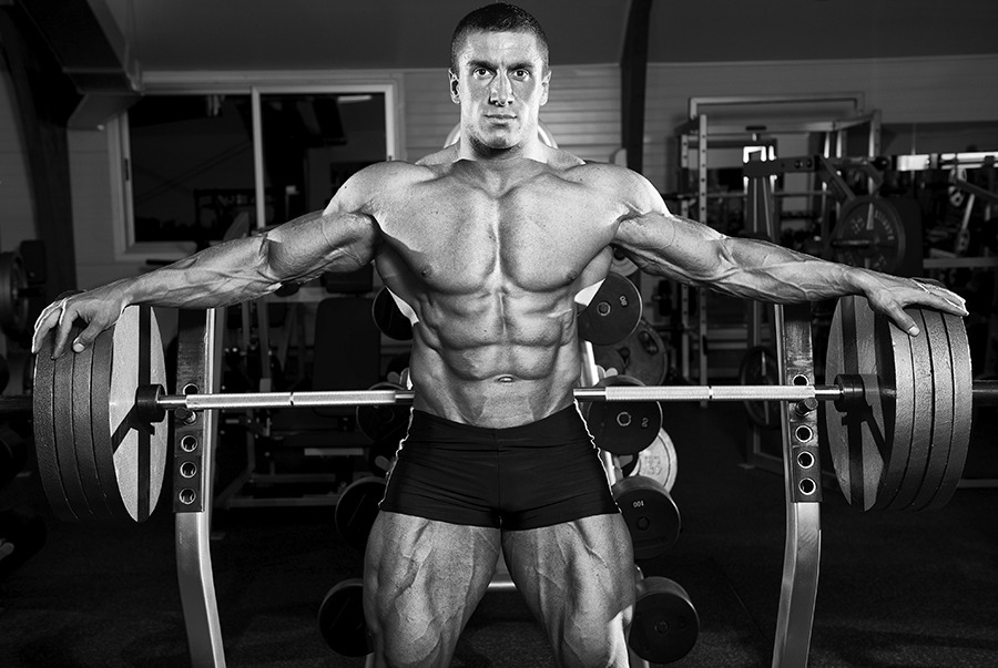 Bodybuilder posing with barbell weights.