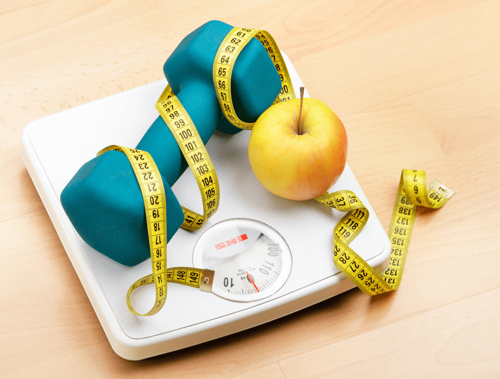 Scale with dumbbell, apple, and measuring tape.