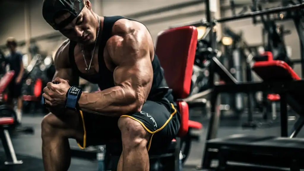 Bodybuilder resting on gym equipment bench.